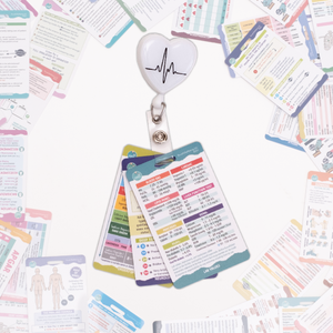 A set of nursing badge cards attached to a retractable badge reel with a heart and ECG line design. The cards display colorful medical reference information. Additional badge cards and study materials are scattered in the background.