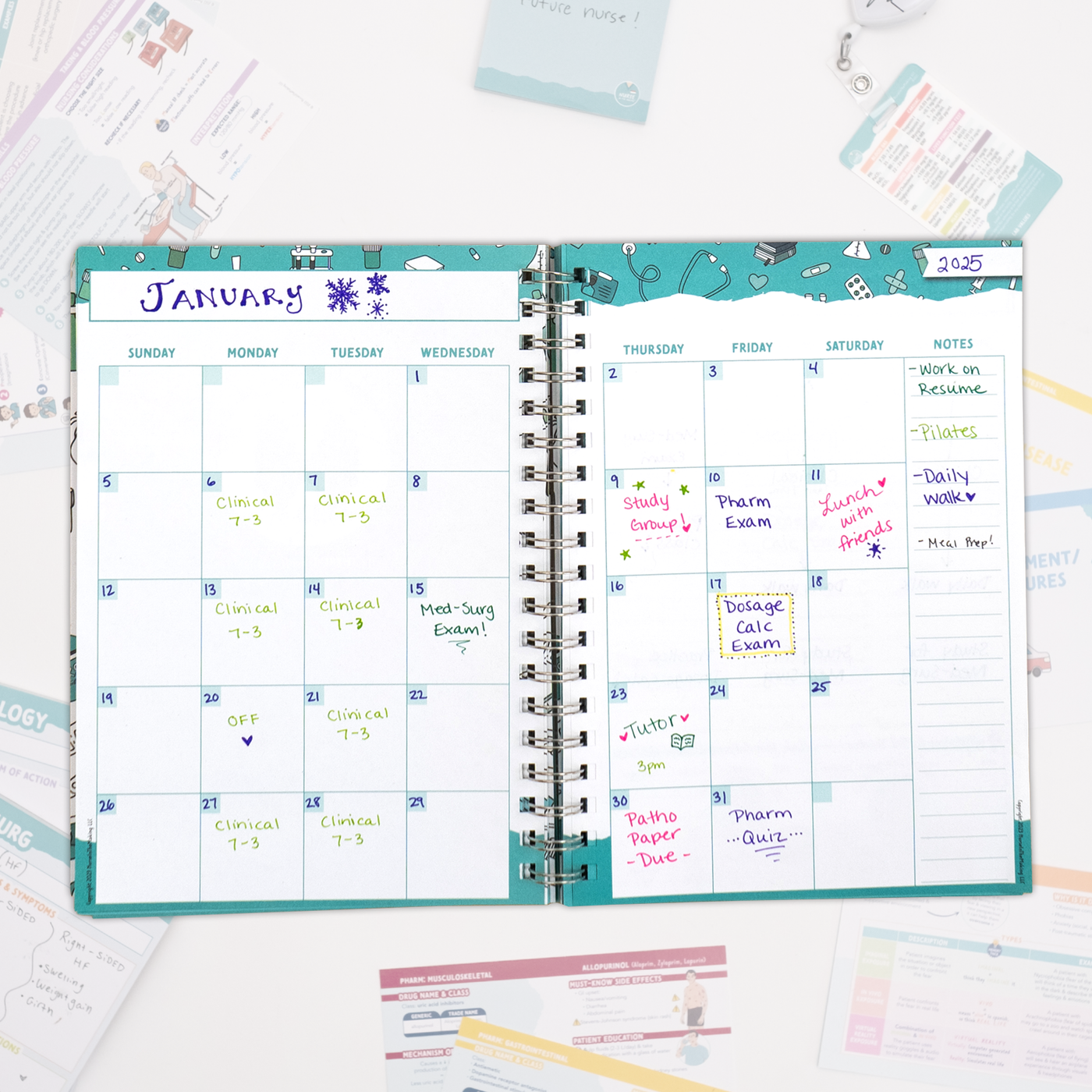 An open spiral-bound planner displays a monthly calendar view for January. The pages are filled with handwritten notes in different colors marking study sessions, exams, and clinical rotations. Various study materials and flashcards surround the planner on a white surface.